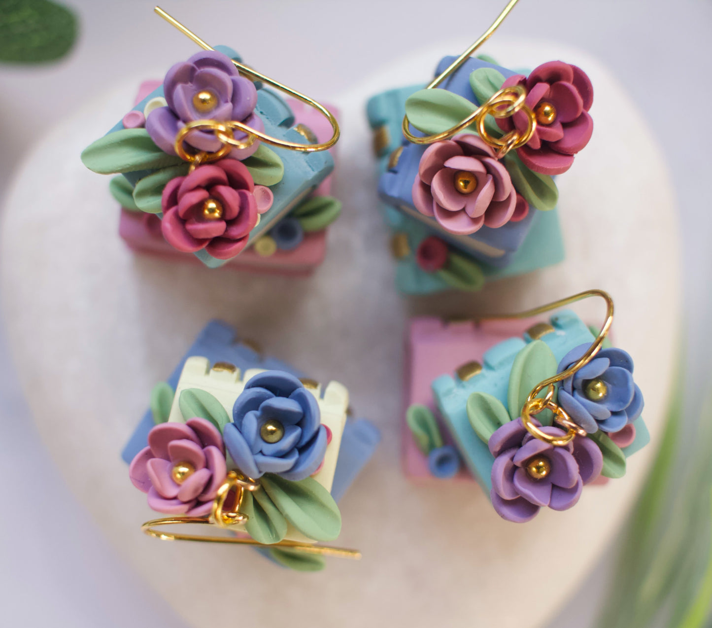 Colorful flower-topped bookstack earrings on a white background