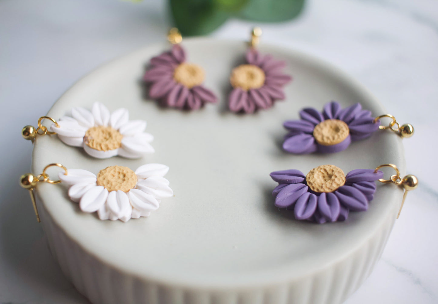 Set of flower-shaped earrings on a white surface