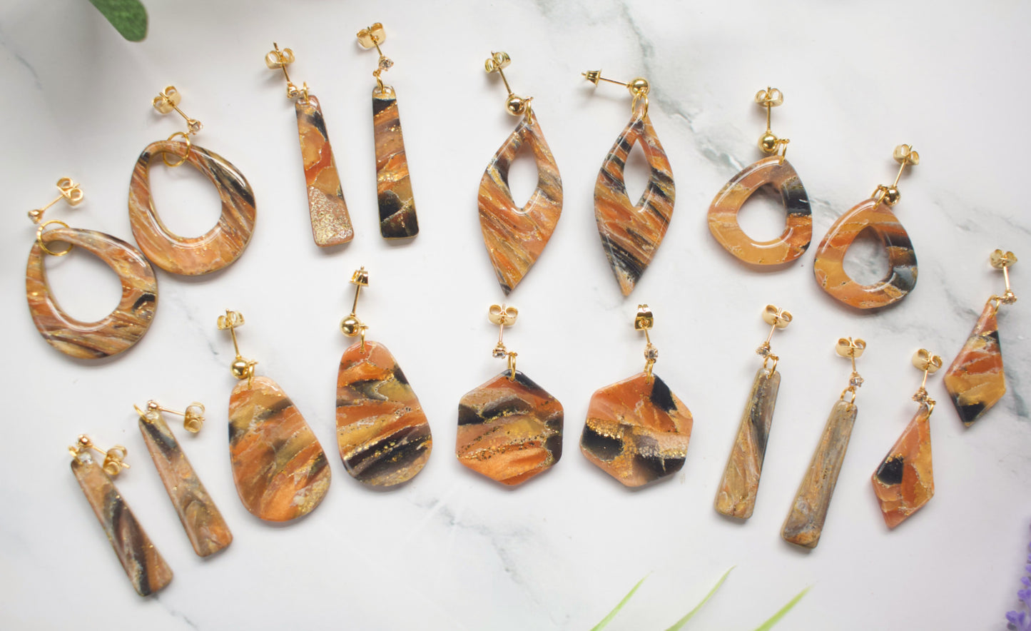 Collection of marbled orange and black earrings on a white surface