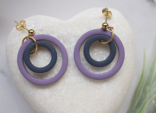 Pair of earrings with purple and navy loops on a white heart-shaped stone.