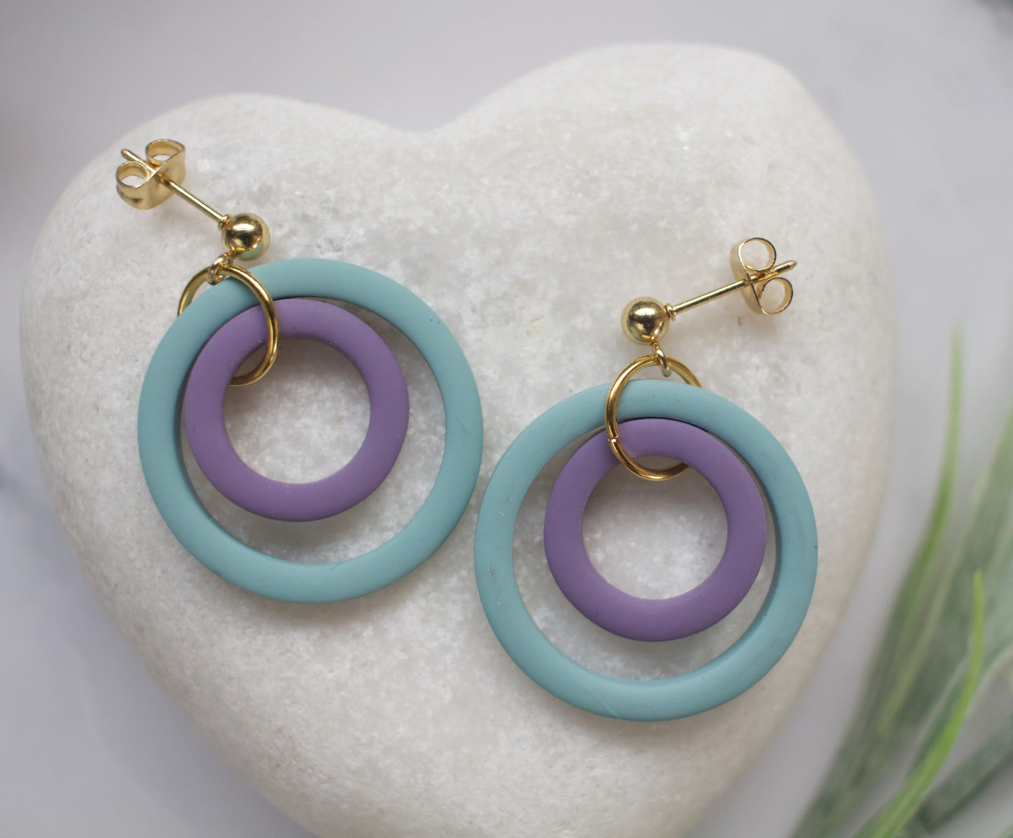 Pair of earrings with blue and purple rings on a heart-shaped white stone.