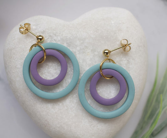 Pair of earrings with blue and purple rings on a heart-shaped white stone.