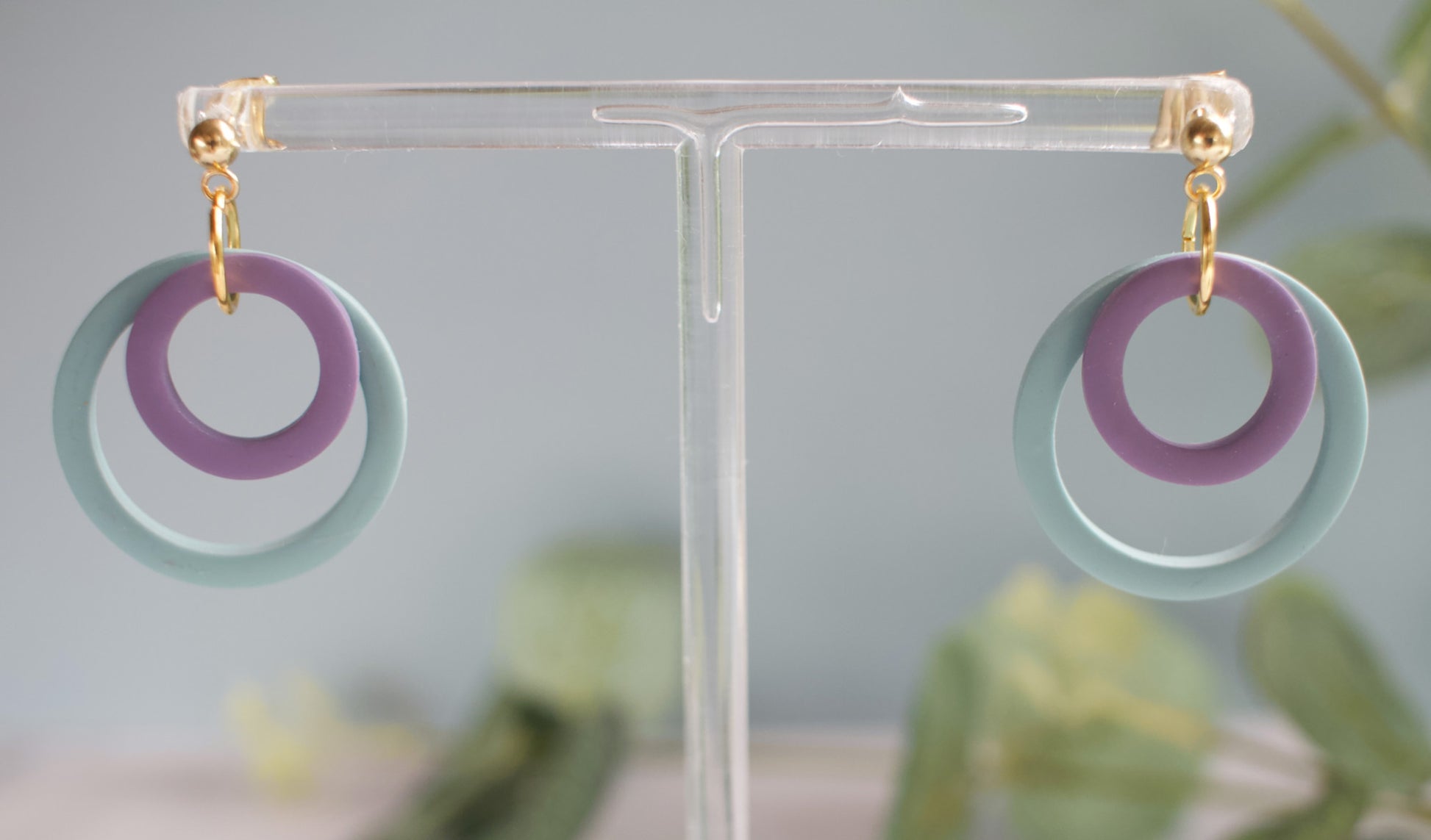Earrings with circular design on a clear stand against a neutral background