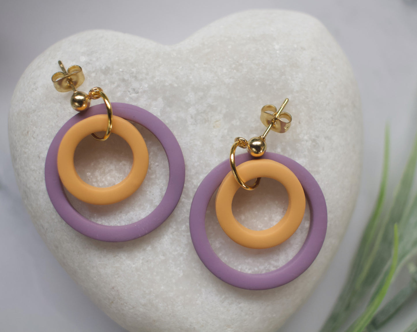 Pair of earrings with purple and yellow rings on a heart-shaped stone.