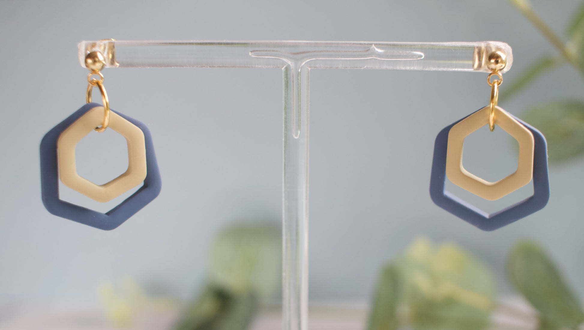 Hexagonal earrings on a clear stand with a blurred background