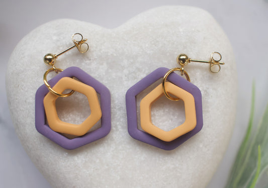 Hexagonal earrings with purple and gold design on a white heart-shaped stone