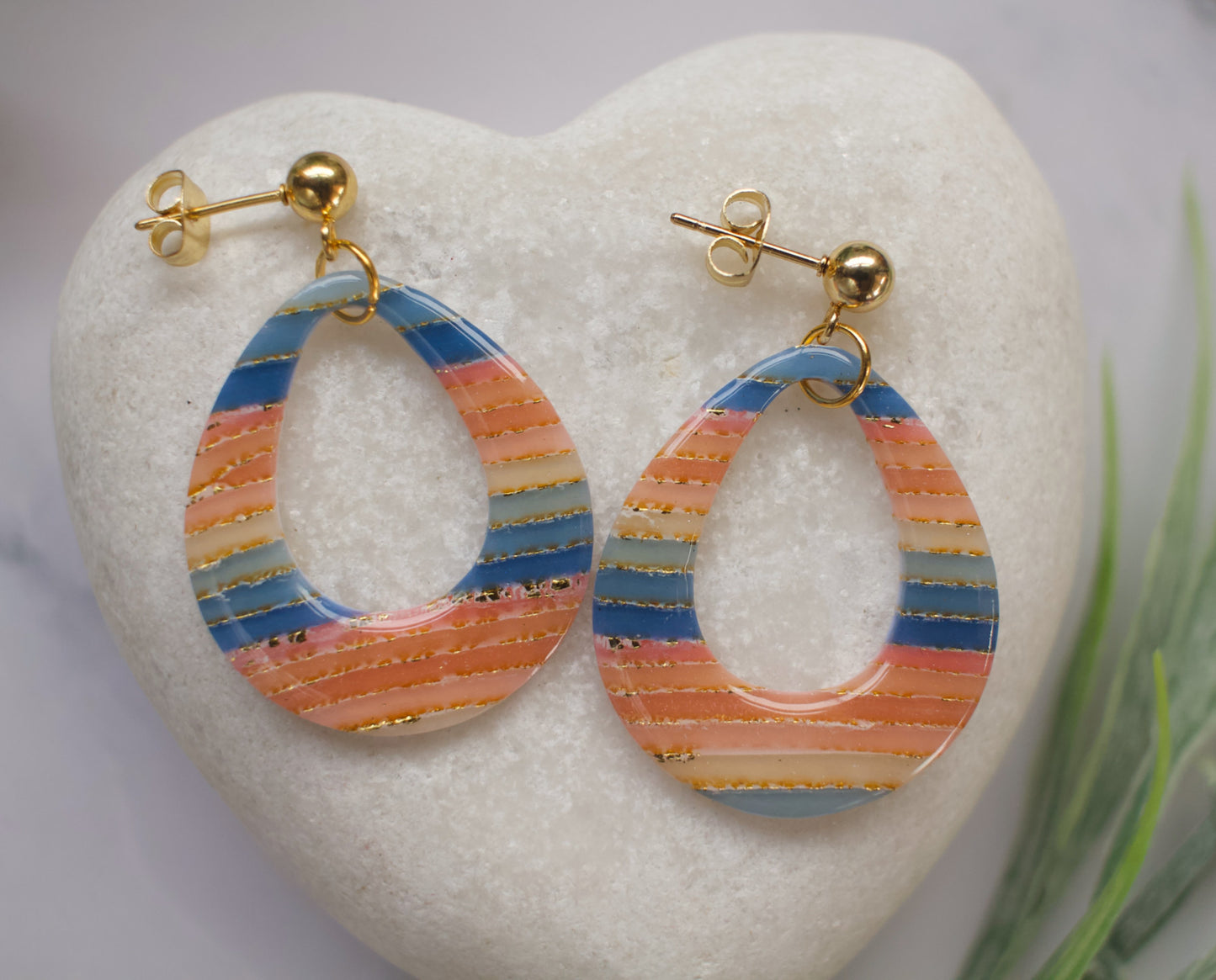Colorful hoop earrings on a heart-shaped stone with a blurred natural background