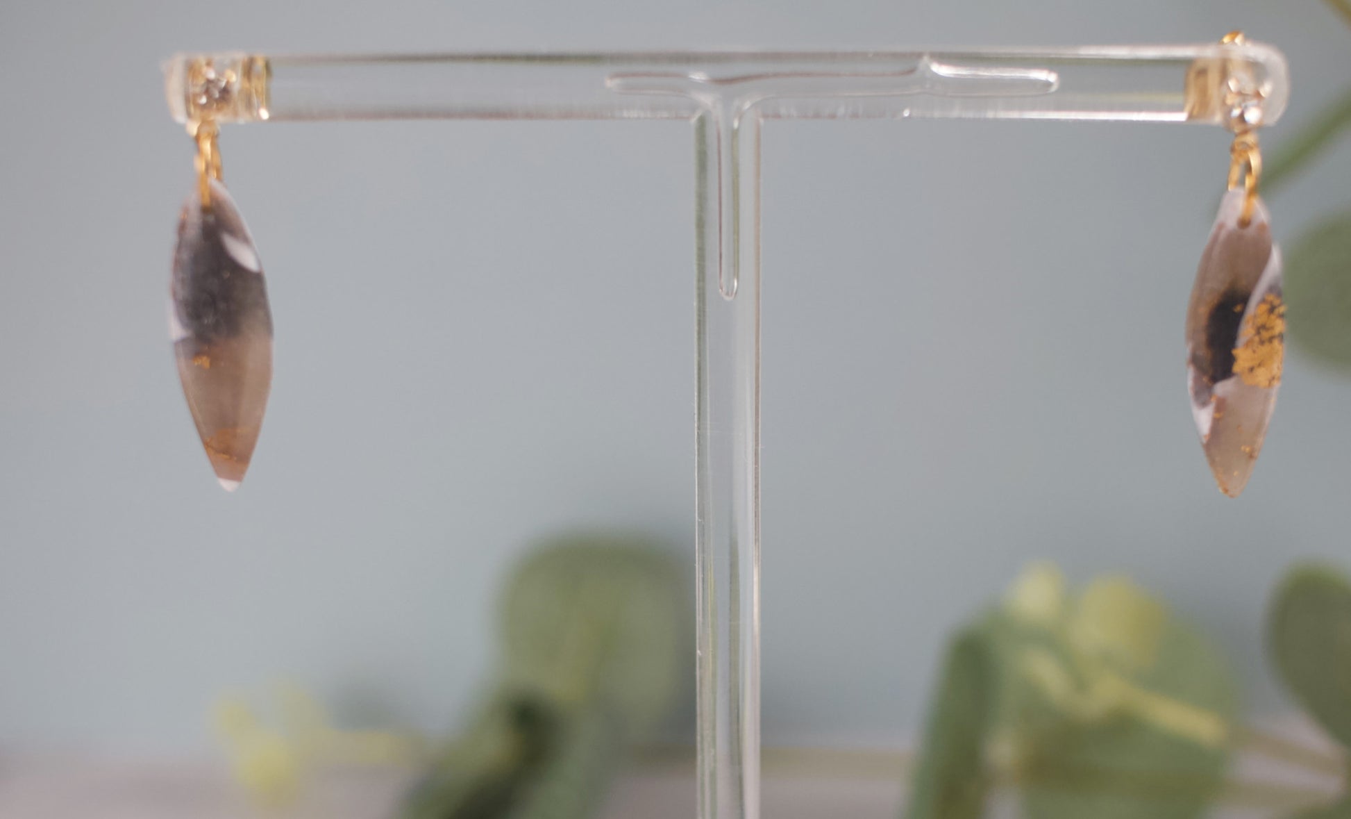 Pair of earrings on a clear stand with a blurred background