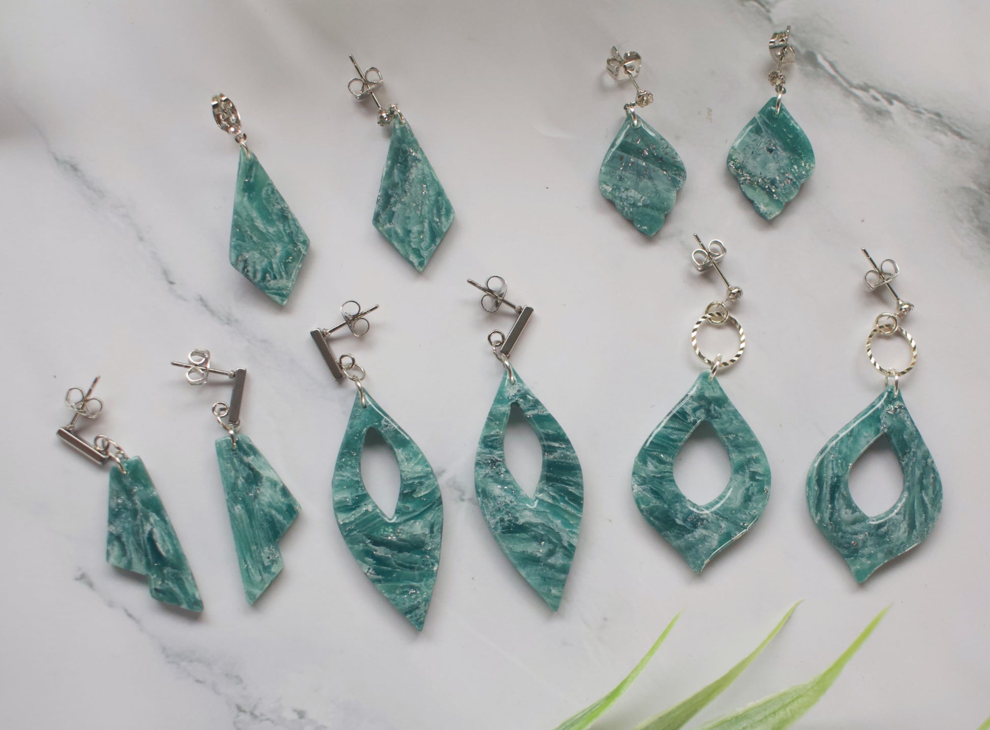 Teal marbled earrings on a marble surface
