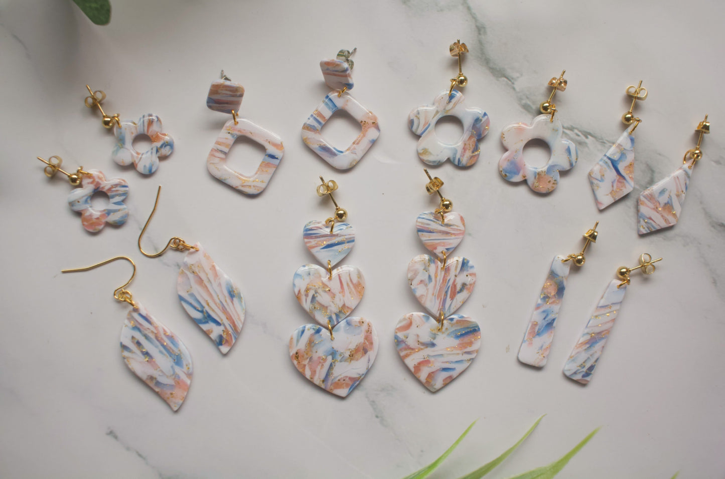 Set of colorful marbled earrings on a marble surface
