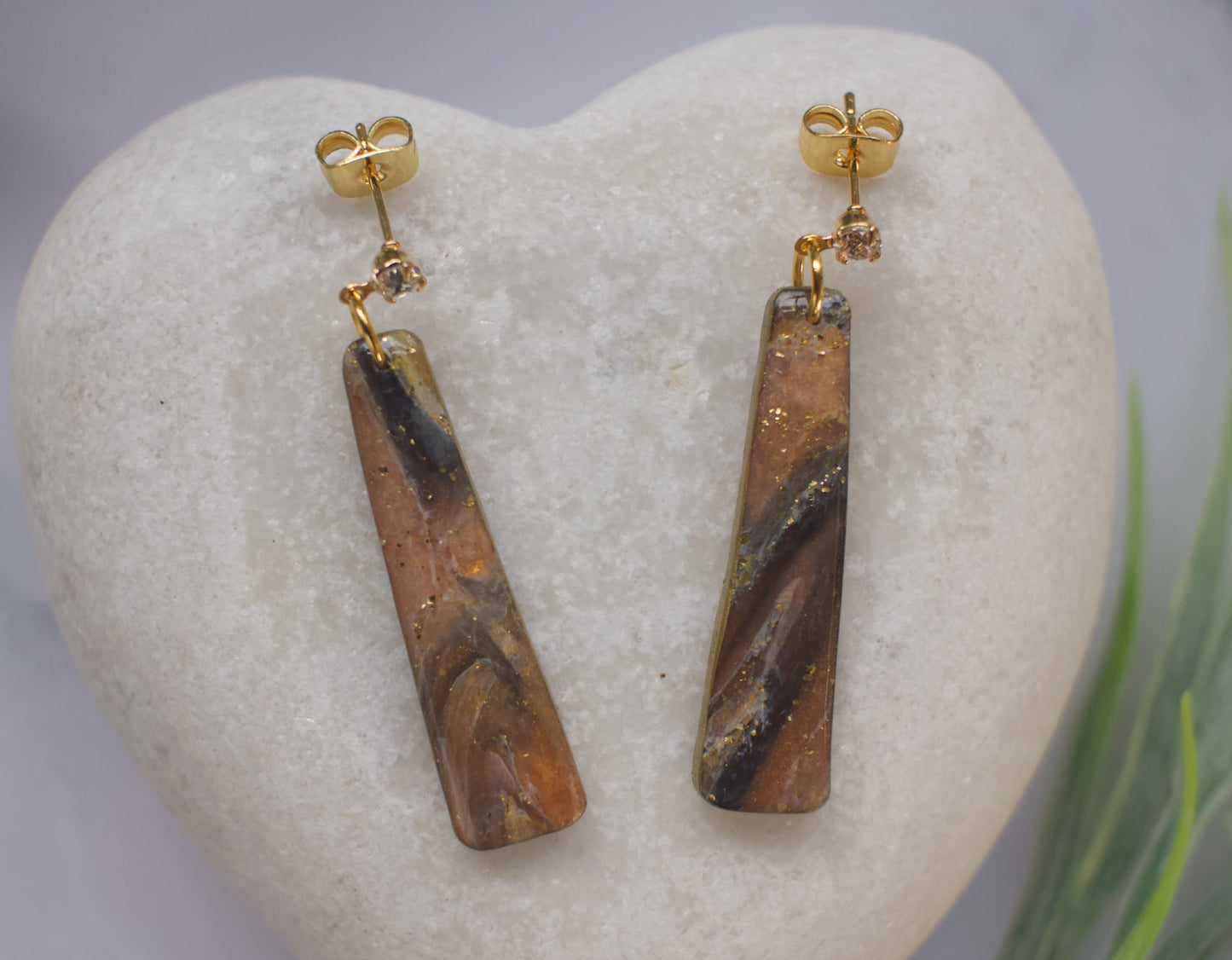Pair of gold and black marbled stone earrings on a heart-shaped stone