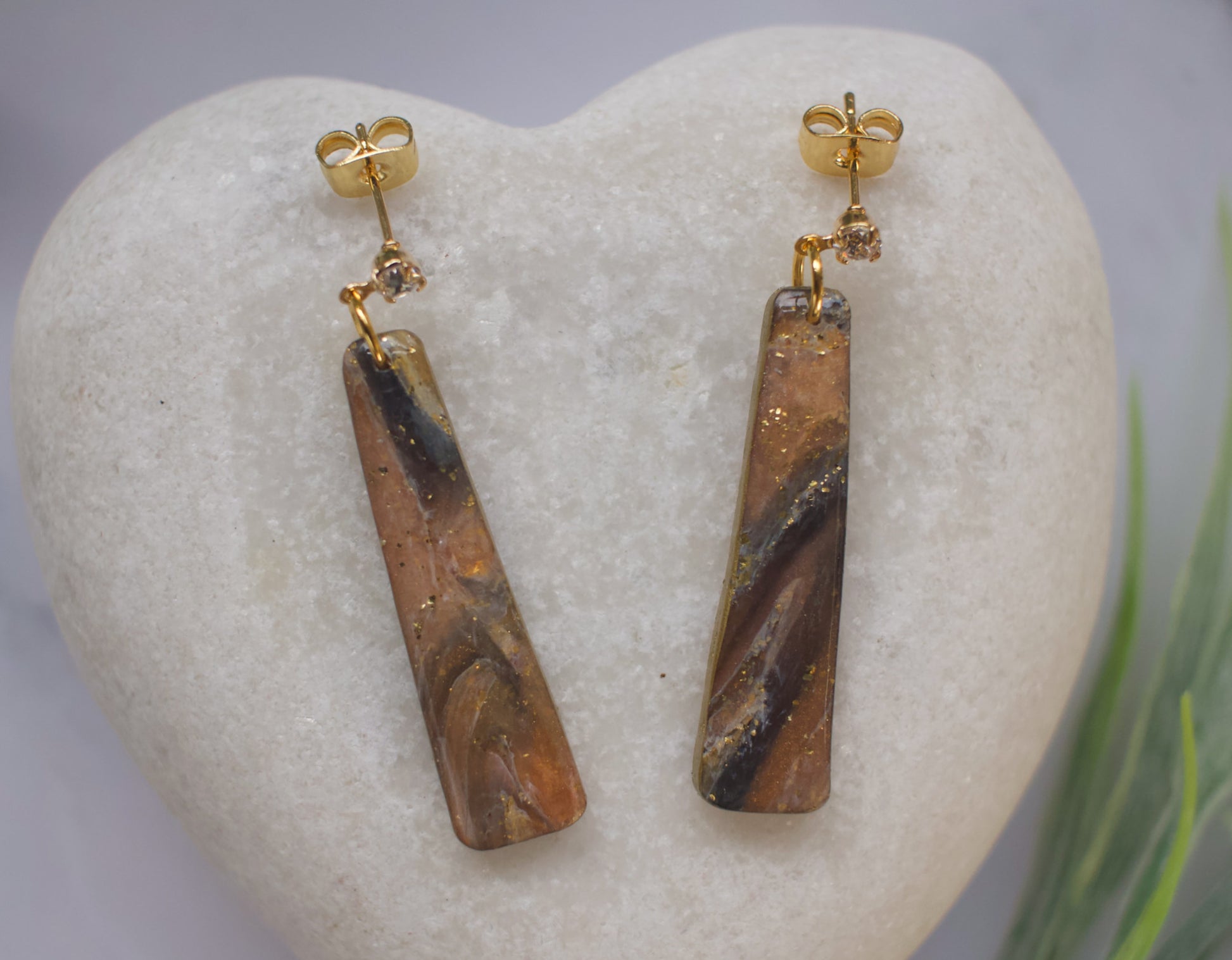 Pair of gold and black marbled stone earrings on a heart-shaped stone