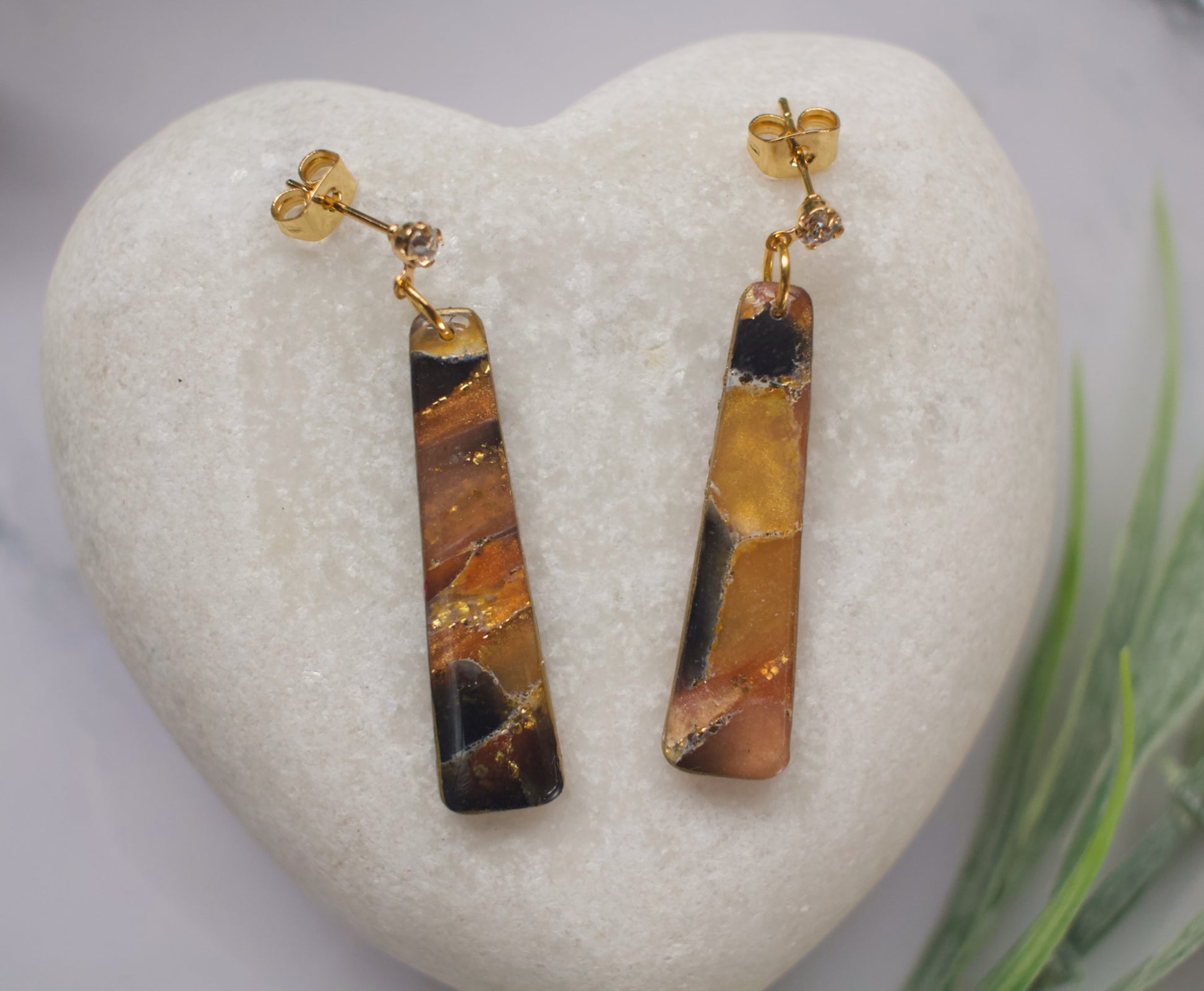 Pair of long drop tiger eye stone earrings on a heart-shaped stone with a natural background.