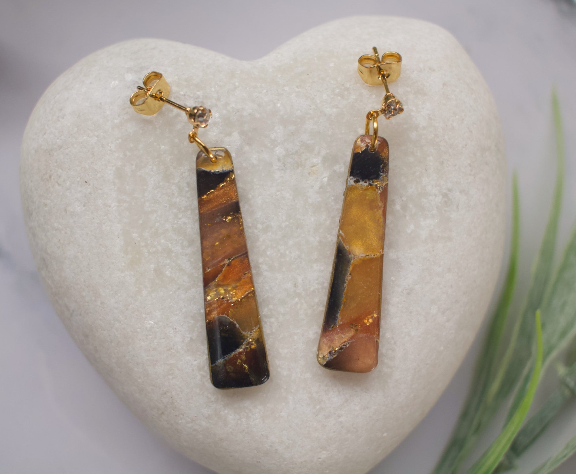 Pair of long drop tiger eye stone earrings on a heart-shaped stone with a natural background.
