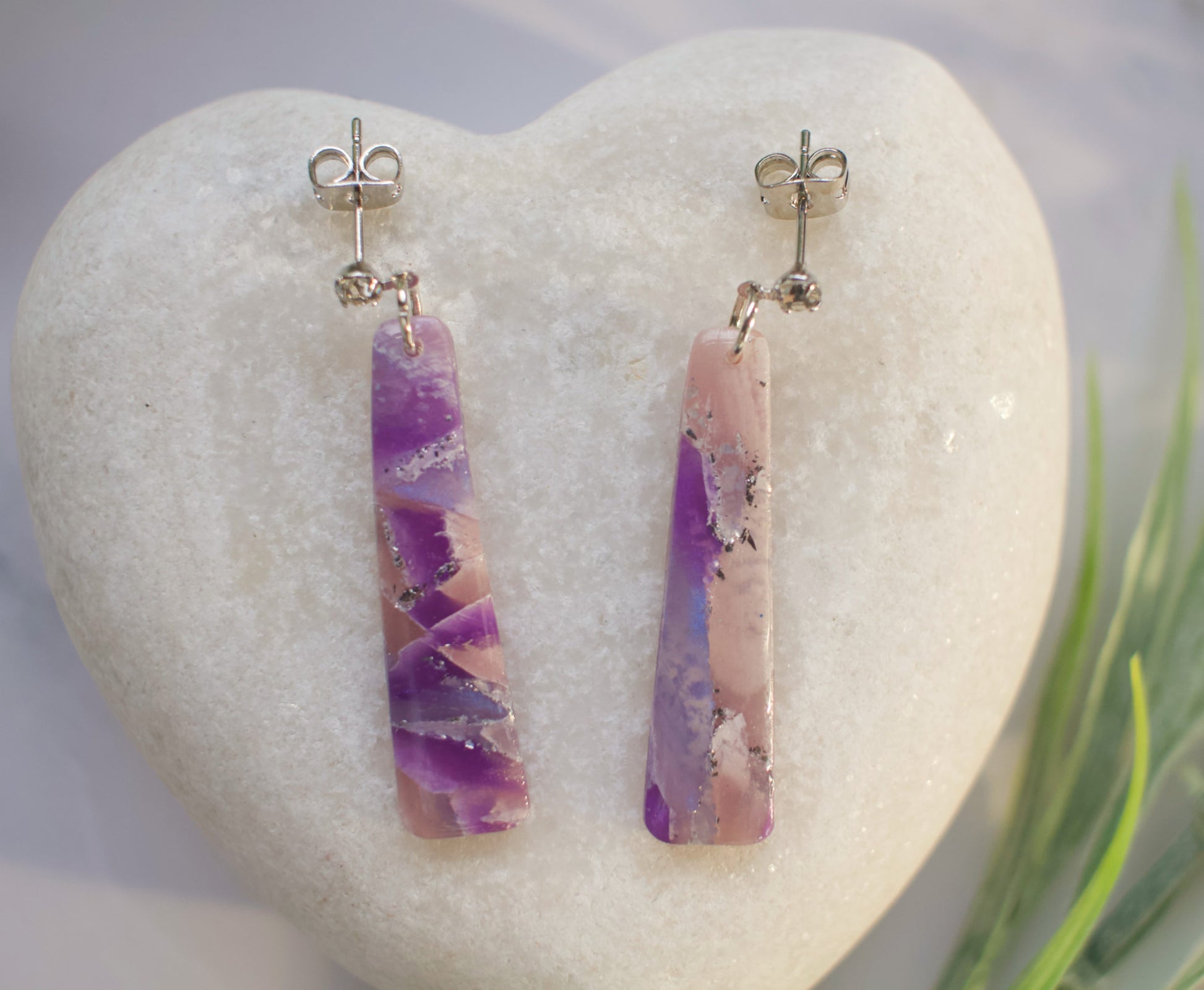 Pair of purple and pink marbled earrings on a white stone background