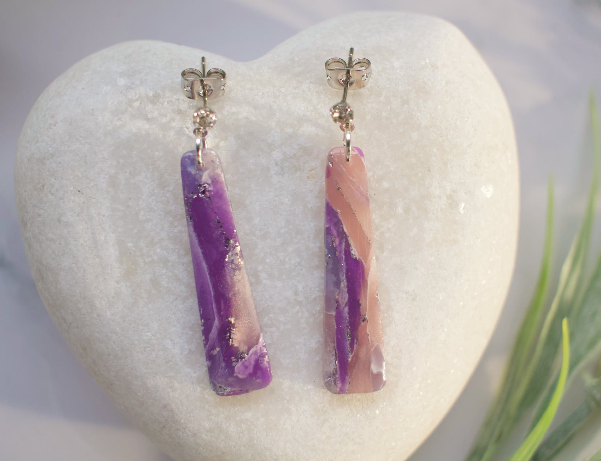 Pair of purple and pink bar-shaped earrings on a white heart-shaped stone.