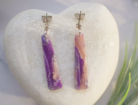 Pair of purple and pink bar-shaped earrings on a white heart-shaped stone.