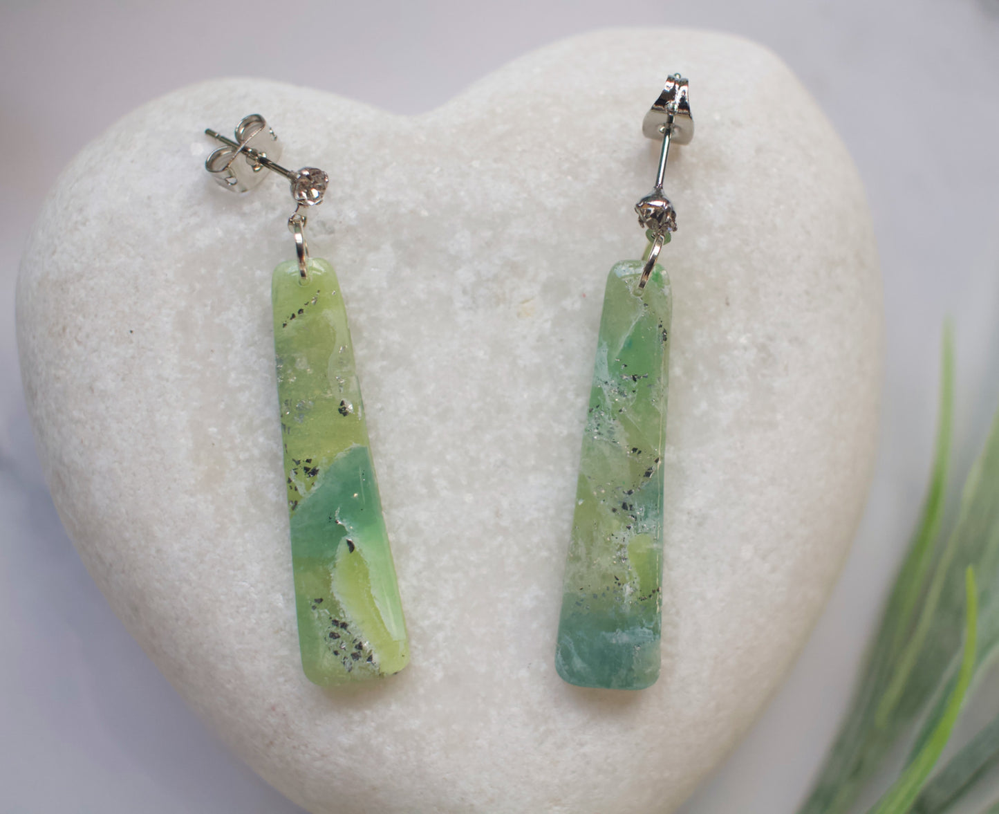 Green bar-shaped earrings on a white heart-shaped stone