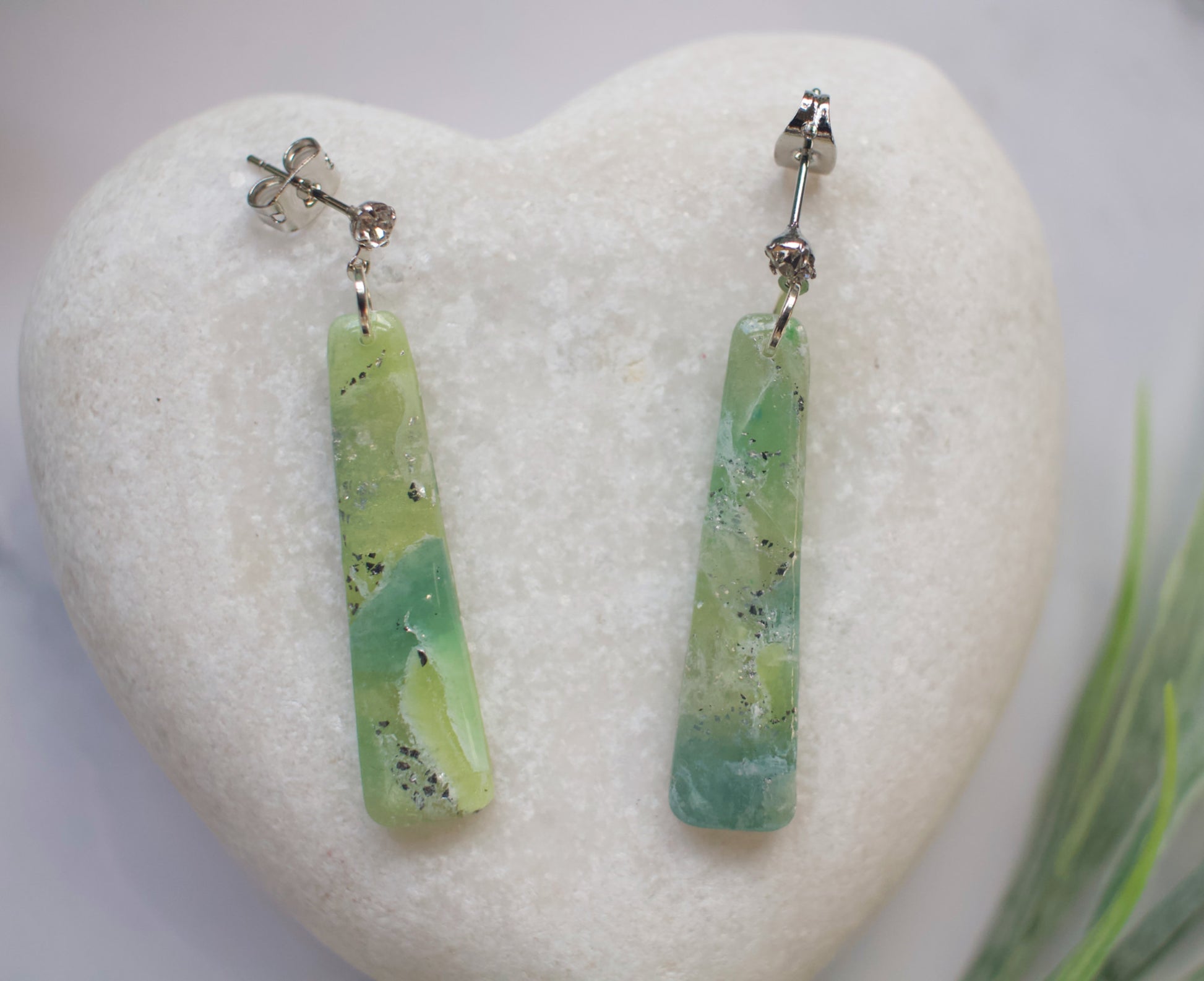 Green bar-shaped earrings on a white heart-shaped stone