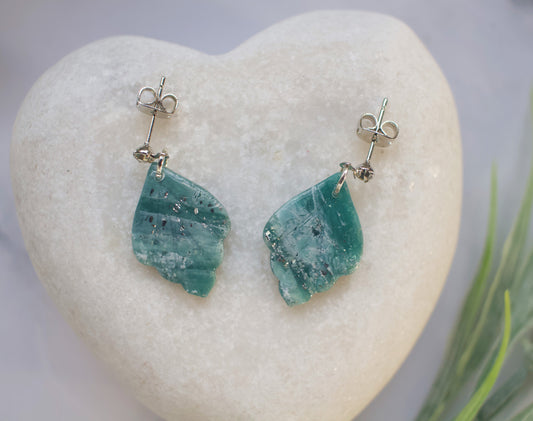 Teal stone earrings on a heart-shaped stone with a blurred natural background