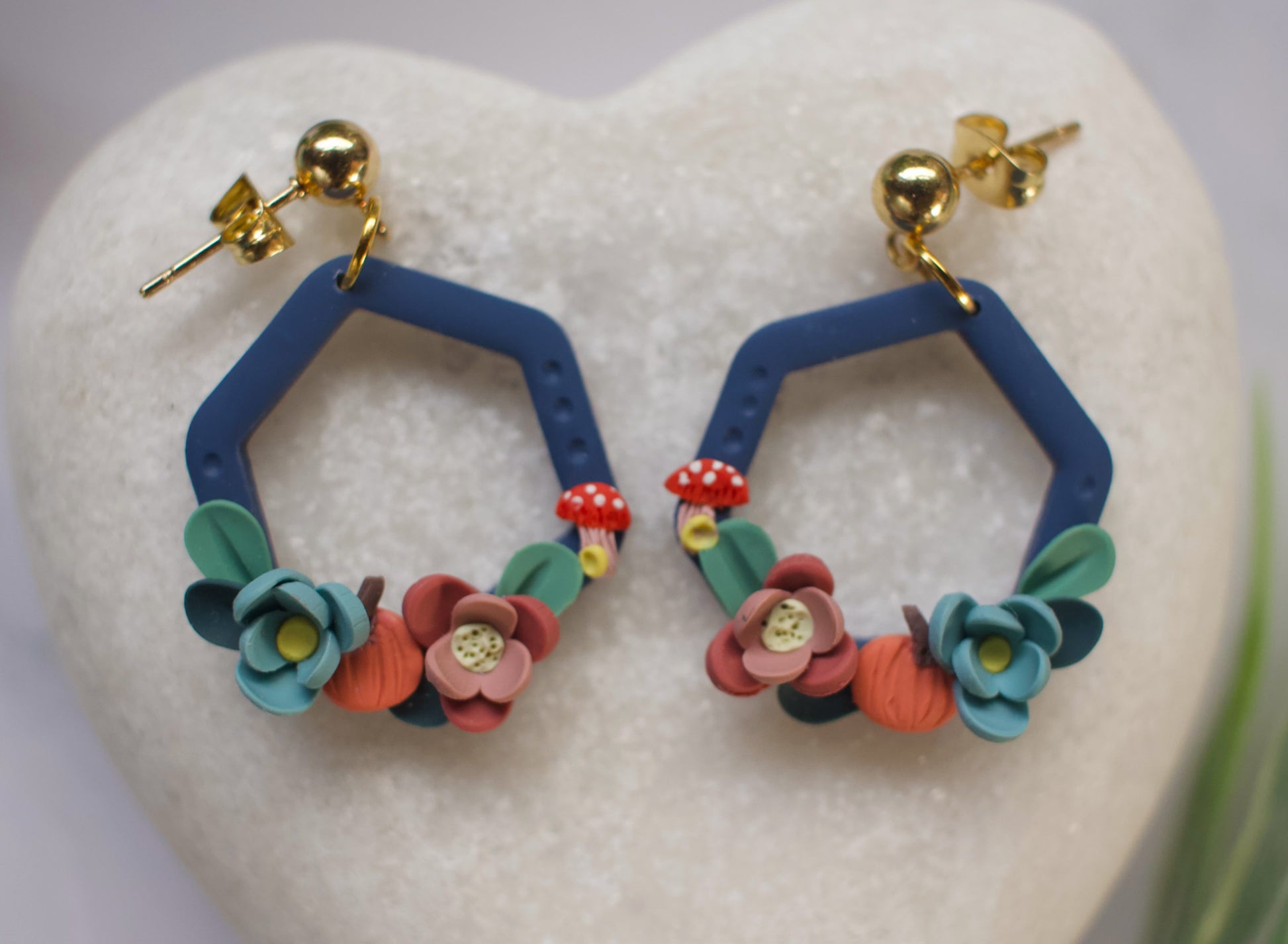 Hexagonal earrings with floral designs on a heart-shaped stone
