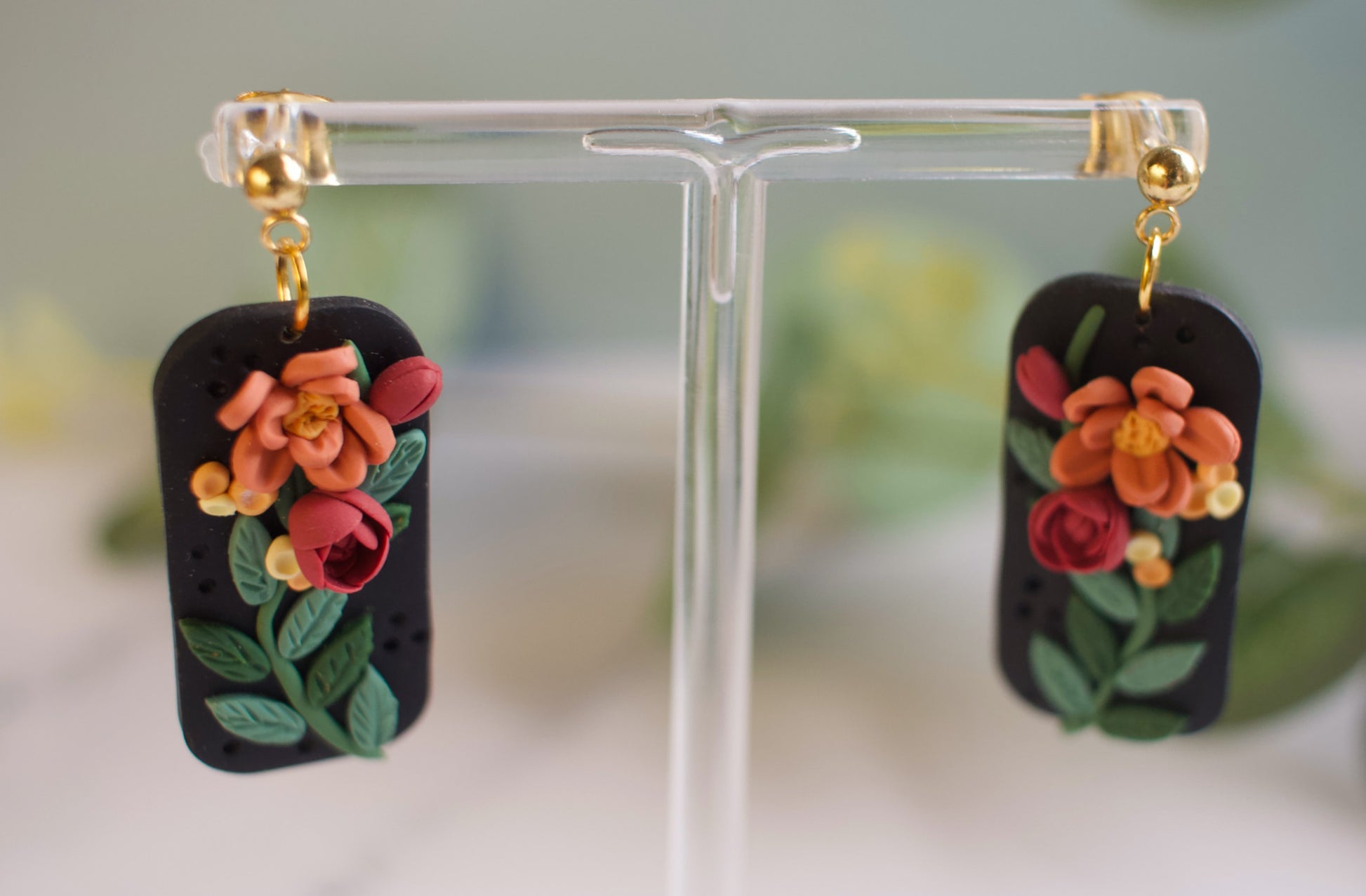 Floral earrings on a clear stand with a blurred background