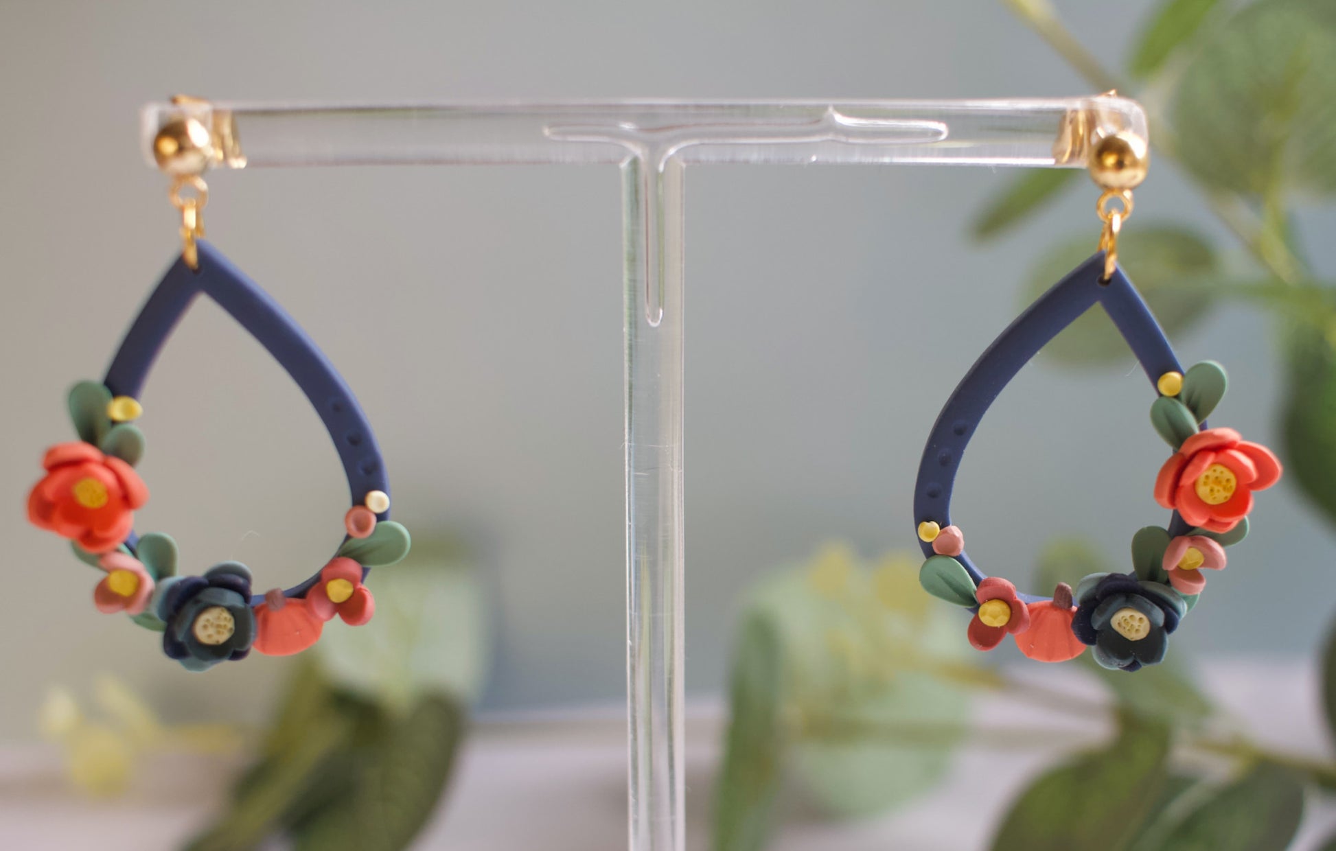 Floral teardrop earrings on a clear stand with a blurred green background