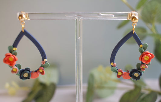 Floral teardrop earrings on a clear stand with a blurred green background