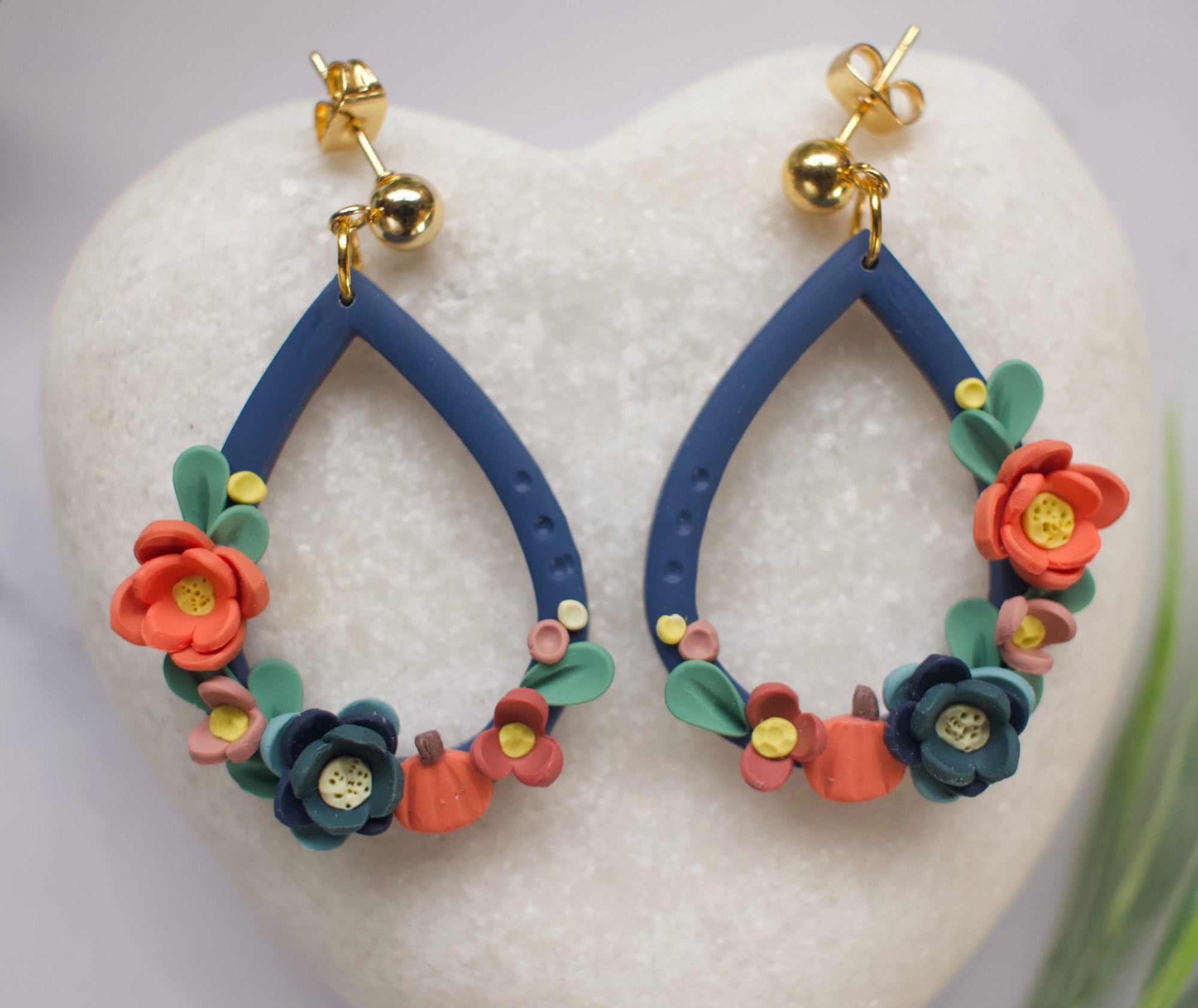Navy blue teardrop earrings with floral designs on a white heart-shaped stone
