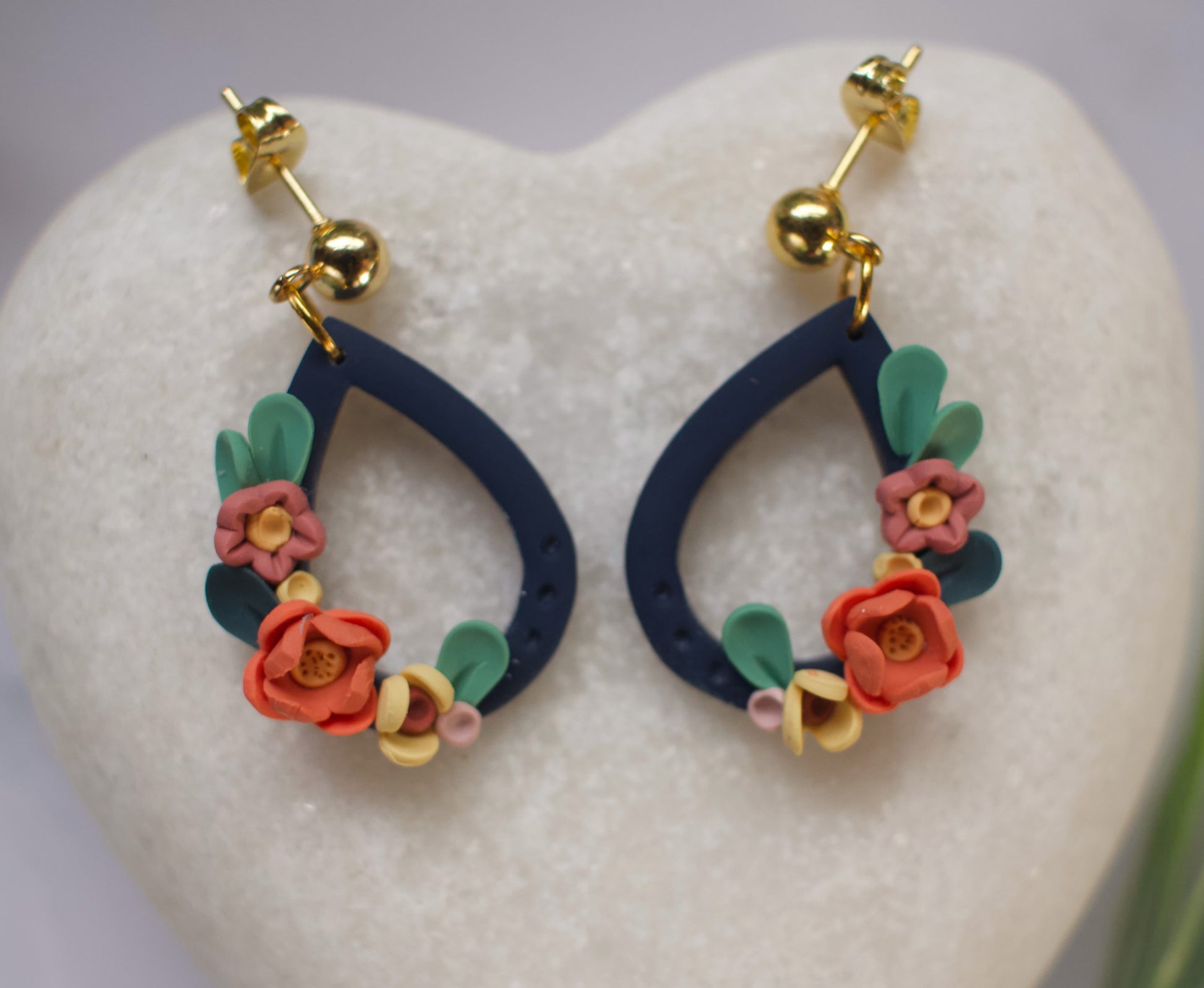 Navy teardrop earrings with floral designs on a heart-shaped stone